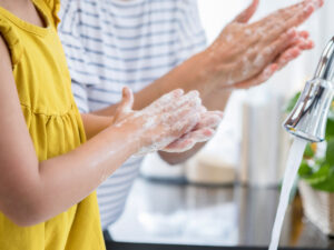 Adult and child washing hands at kitchen sink